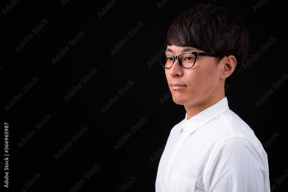 Obraz premium Young handsome Asian businessman against black background
