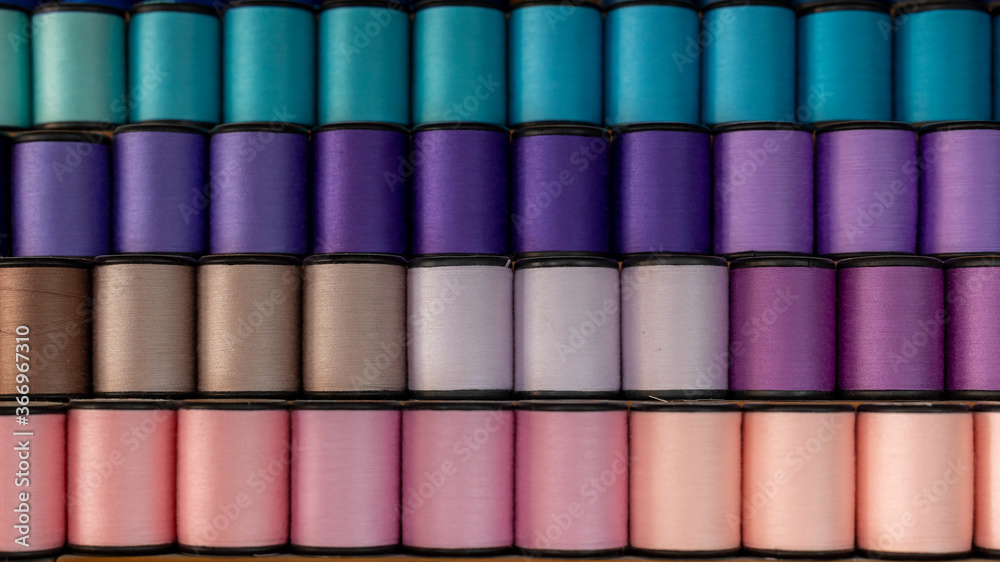 Fototapeta premium Sewing threads colorful sort in diagonal, Color sewing threads background closeup.