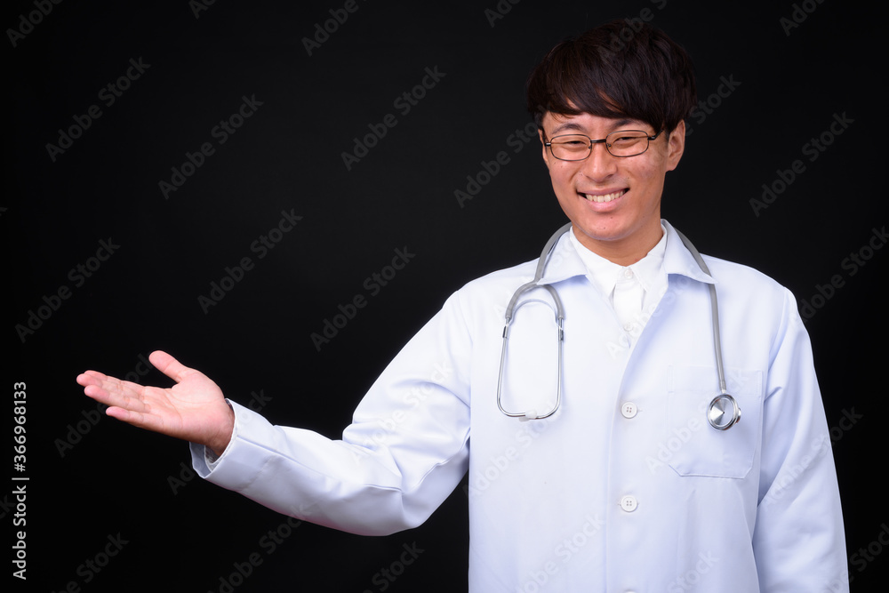 Young handsome Asian man doctor against black background Young handsome Asian man doctor against black background