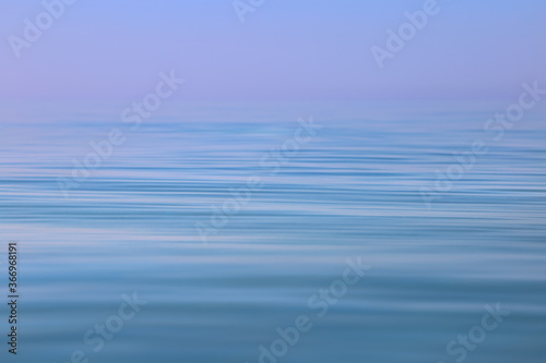 Calm sea wavy surface of the sea under a clear sky close-up. Blue and purple background.