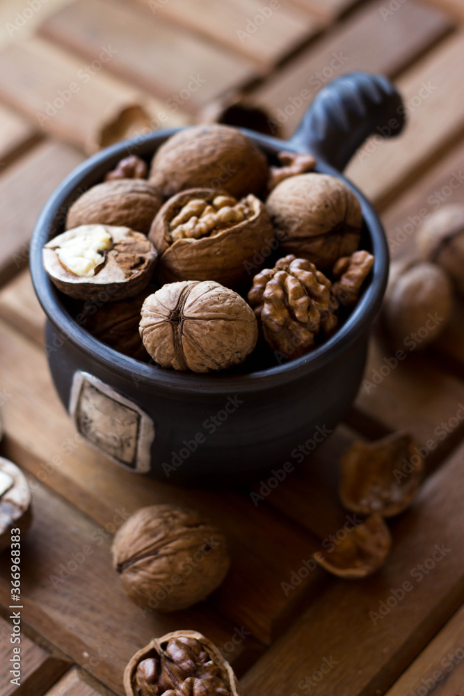 A brown earthenware mug full of nuts. Walnuts and hazelnuts in a high dish A brown earthenware mug full of nuts. Walnuts and hazelnuts in a high dish