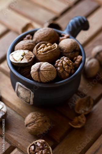 A brown earthenware mug full of nuts. Walnuts and hazelnuts in a high dish
