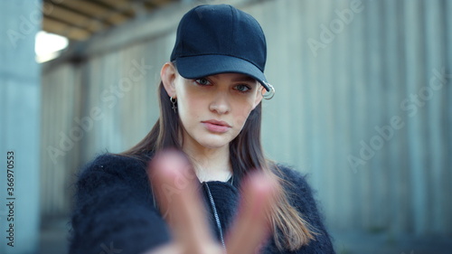 Girl showing v sign at camera on street. Woman showing peace sign with fingers © stockbusters