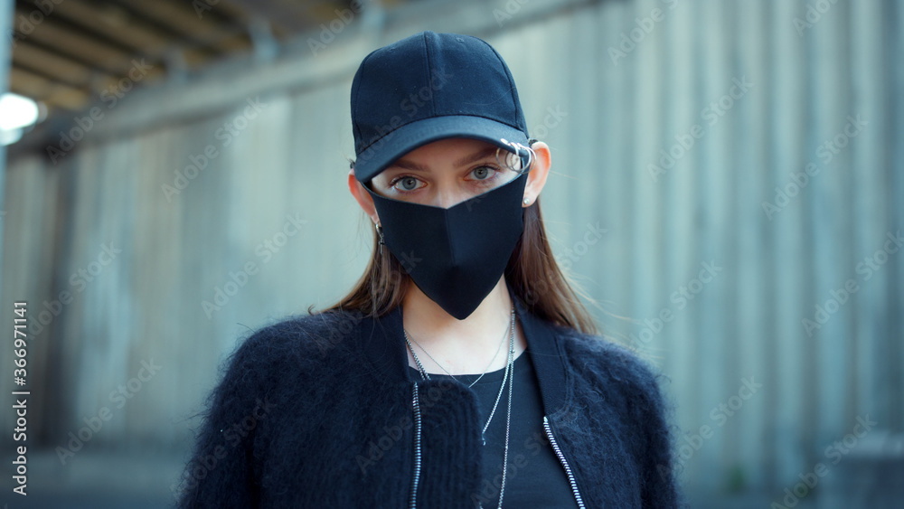 Girl in protective mask looking at camera on street. Woman wearing mask