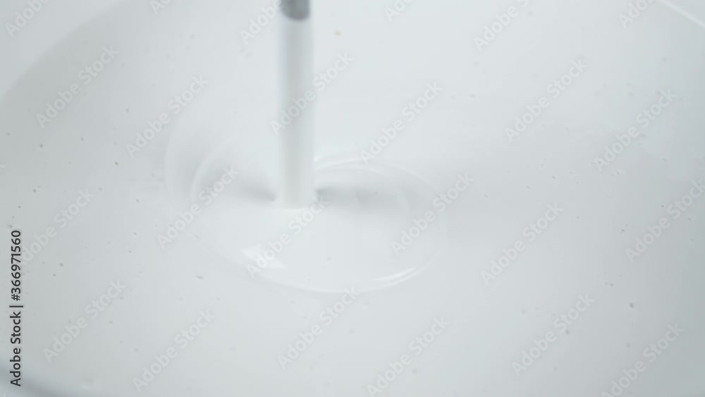 Construction Worker Mixes Acrylic White Paint in a Bucket Needed to Paint the Walls of a Room Construction Worker Mixes Acrylic White Paint in a Bucket Needed to Paint the Walls of a Room