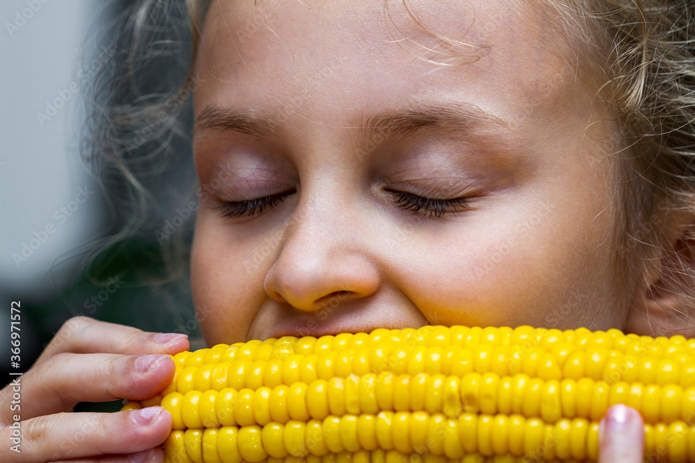 Young girl eating a boiled corn with eyes closed Young girl eating a boiled corn with eyes closed