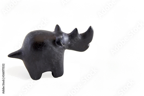 A stone-carved black statue of a rhino, with an white background.