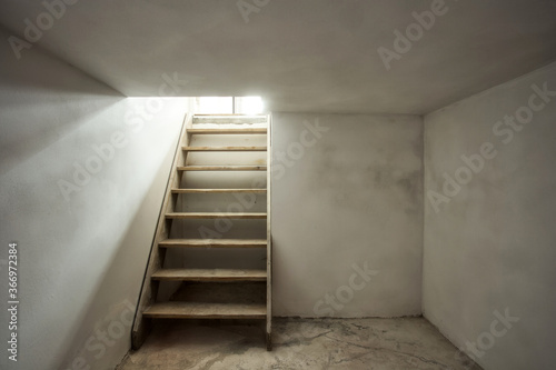 empty basement in abandoned old industrial building with little light and a wooden stairs photo