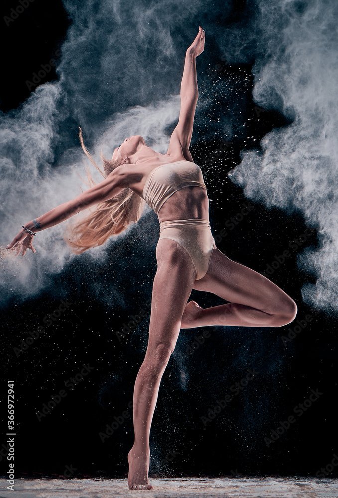 dancing girl in flour (powder). Black studio. Ballet dance.