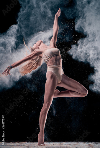 dancing girl in flour  powder . Black studio. Ballet dance.