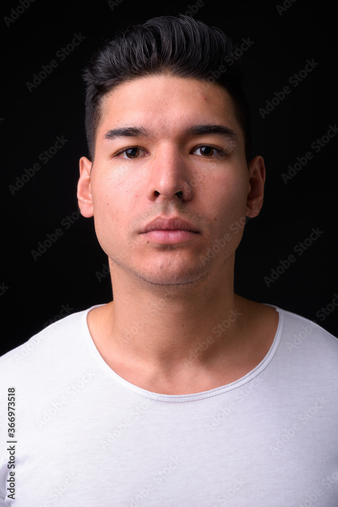Young handsome multi ethnic man against black background