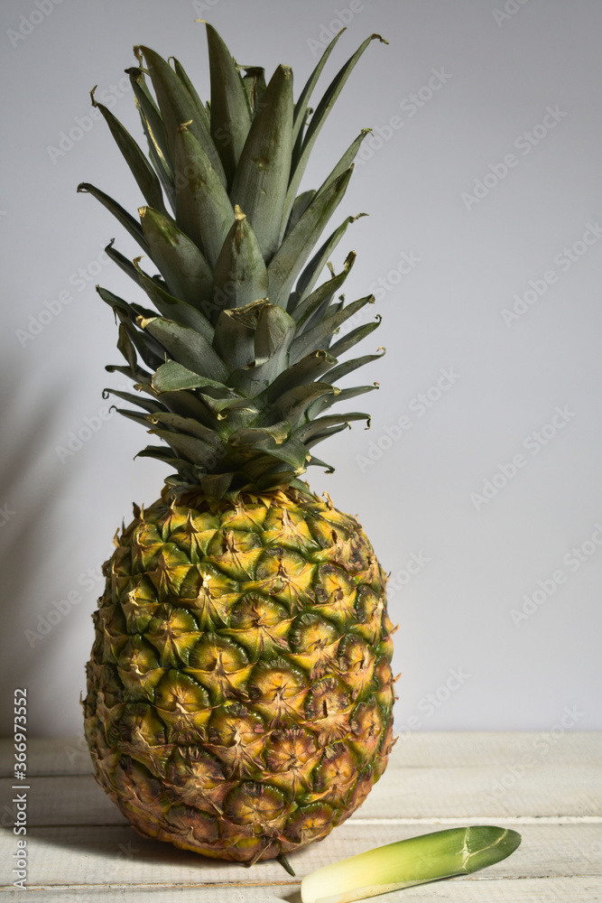 piña entera en un fondo blanco perla, sobre una base de madera blanco ...