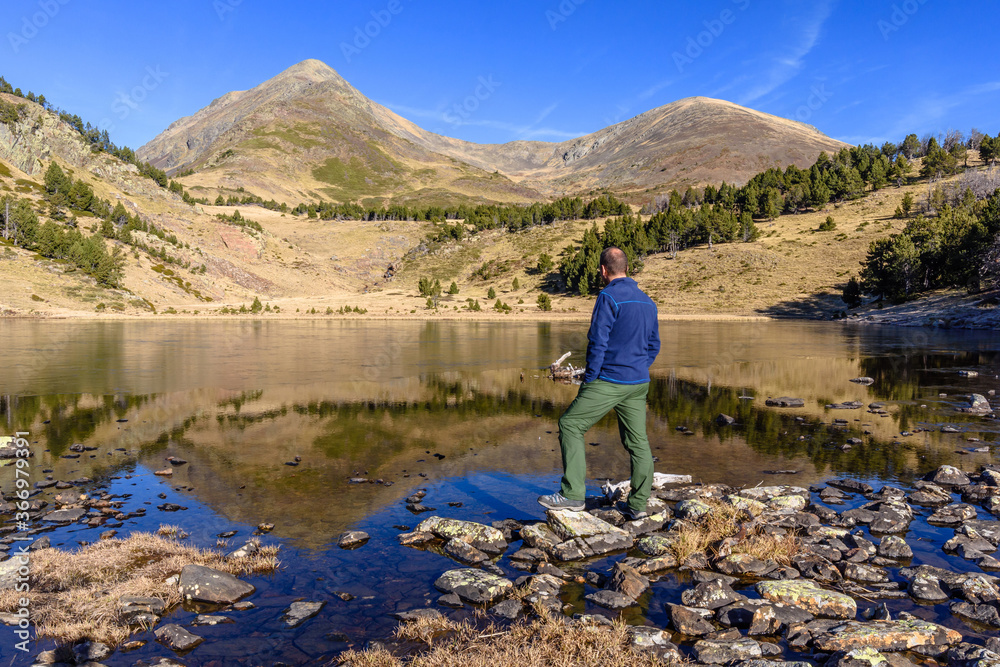 Fototapeta premium Hiker enjoying beautiful view at the lake (The Peak of Peric reflections, Capcir, France)