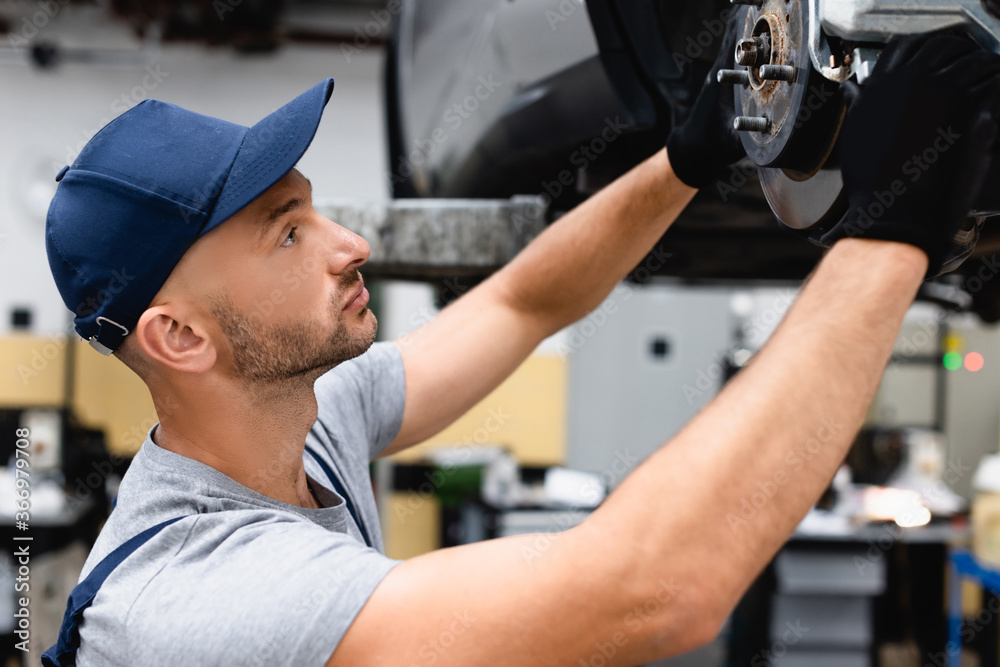 profile of mechanic in cap repairing car in service station profile of mechanic in cap repairing car in service station
