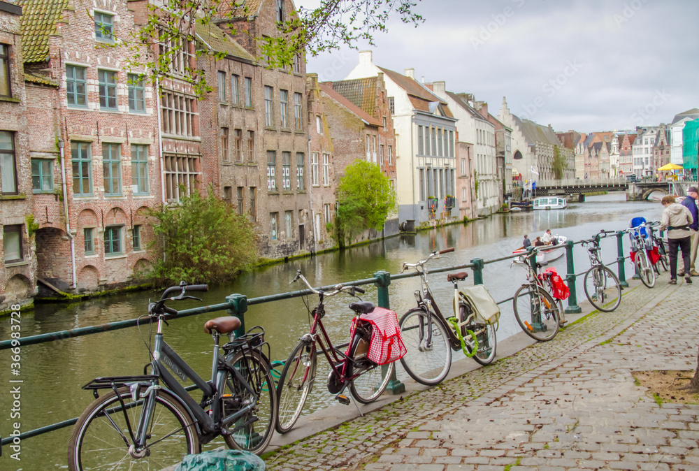 Ghent, Belgium;  A group of tourists parked their bicycles adjacent to a canal in Ghent.