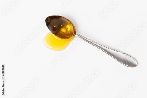 Spoonful of honey is spilled on a white background