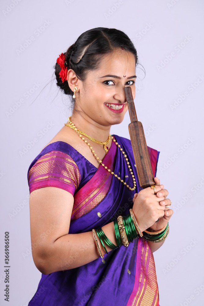 Beautiful Indian woman or girl holding rolling pin in hand. This is