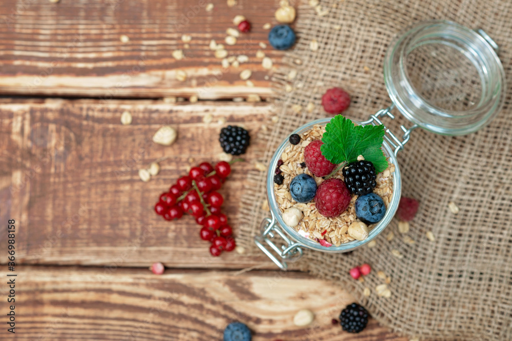 Muesli granola with yogurt and fresh red currant berries raspberries blueberries and blackberries, nuts in a glass jar on a wooden background. Healthy breakfast. Muesli granola with yogurt and fresh red currant berries raspberries blueberries and blackberries, nuts in a glass jar on a wooden background. Healthy breakfast.