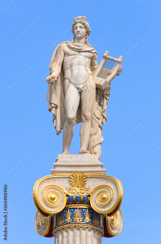 Apollo statue with golden decorations against blue sky Apollo statue with golden decorations against blue sky