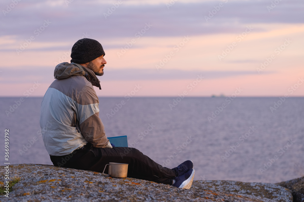 A man with a book on the background of the sea. The background is blurred. A man with a book on the background of the sea. The background is blurred.