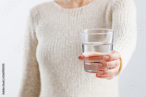 A woman holds a glass of water in her hands.