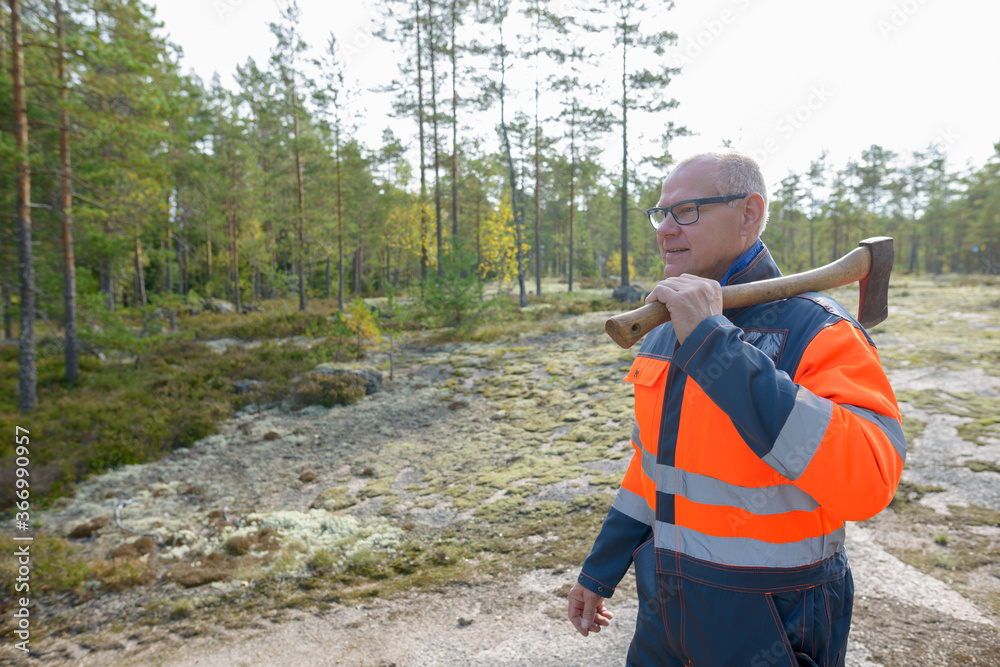 Portrait of happy mature handsome man holding ax in the forest Portrait of happy mature handsome man holding ax in the forest
