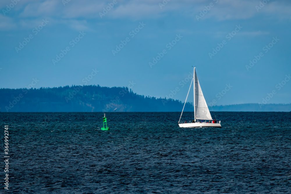 Obraz premium Isolated sailboat profile with blue sky background and green bouy