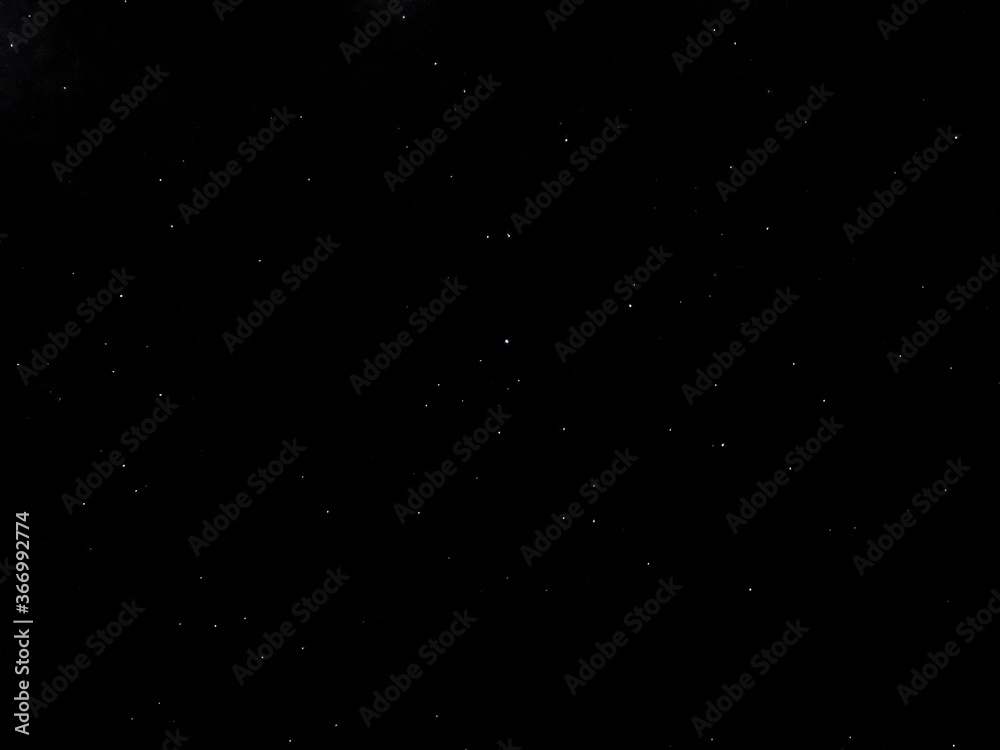 Flying dust particles on a black background. Stars in summer days 