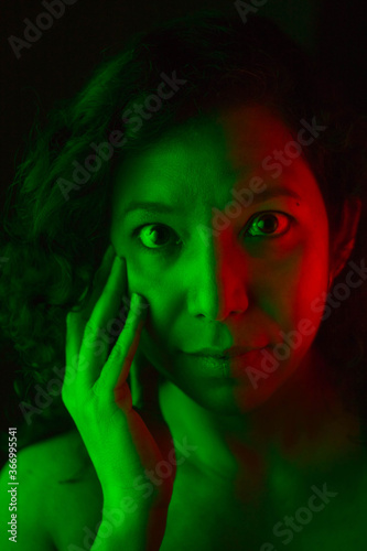 Selective focus portrait of young caucasian woman with green and red lights on his face