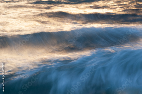 Sunrise over the sea. Stormy sea surface with billowing waves is illuminated by the gliding rays of the rising sun
