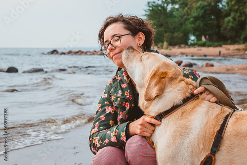 Cuadro en lienzo A dog kisses a girl on the cheek against the background of the sea