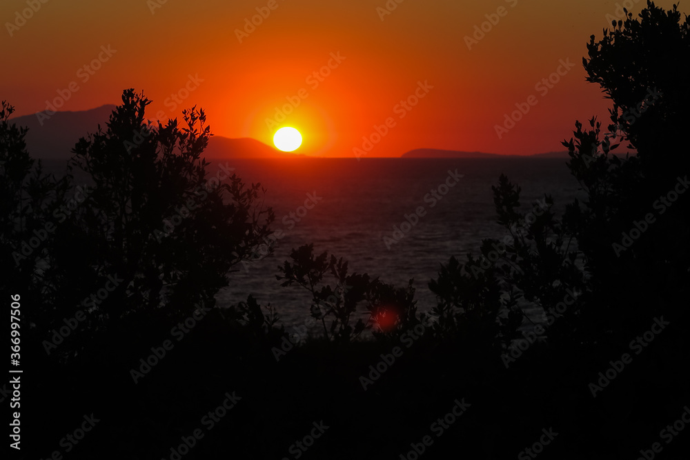 Sunset behind the mountains at the bottom of the Mediterranean sea with silhouettes of trees, commune of Sorrento, province of Naples, Italy Sunset behind the mountains at the bottom of the Mediterranean sea with silhouettes of trees, commune of Sorrento, province of Naples, Italy