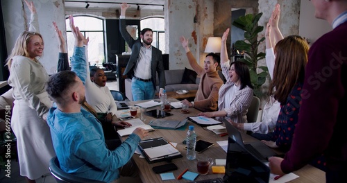 Happy multiethnic team of professional business people put hands together and clap at loft office meeting slow motion.