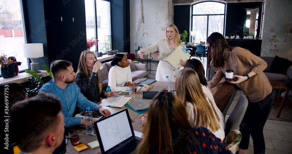 Beautiful successful young blonde female business coach leading seminar for employees at modern loft office slow motion.