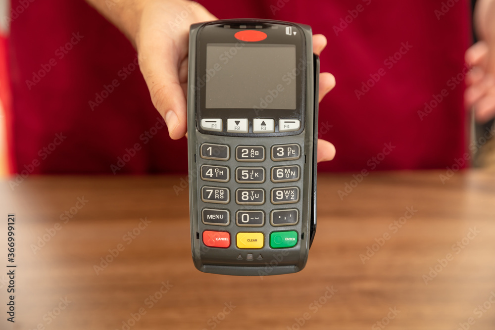 Cashier offering POS terminal for payment with credit card. Cashier offering POS terminal for payment with credit card.