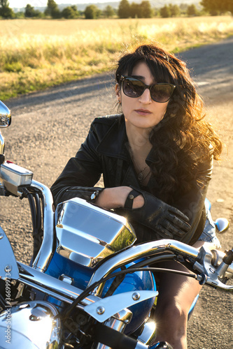 Brunette girl biker in sunglasses sitting on the motorcycle.