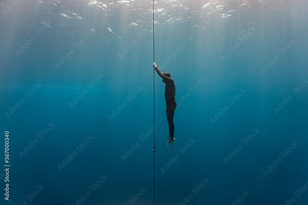 Foto Free diver ascends to the surface by pulling the dive line