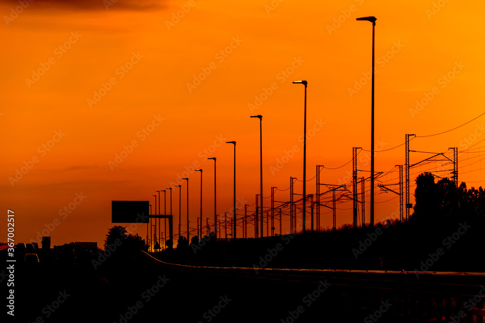 Silhouette High speed railway power line and light poles on orange sky