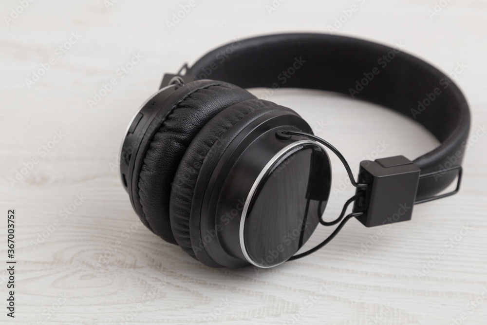 wireless black headphones on a white wooden table, love of music wireless black headphones on a white wooden table, love of music