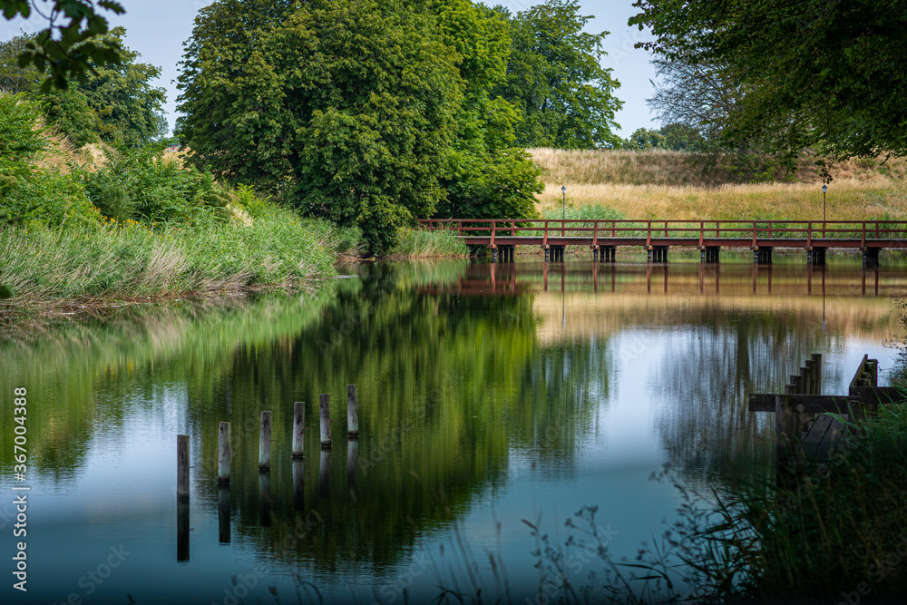 A moat protecting an old fortress in Landskrona, Scania, southern Sweden. Beautiful reflections of trees in the water A moat protecting an old fortress in Landskrona, Scania, southern Sweden. Beautiful reflections of trees in the water