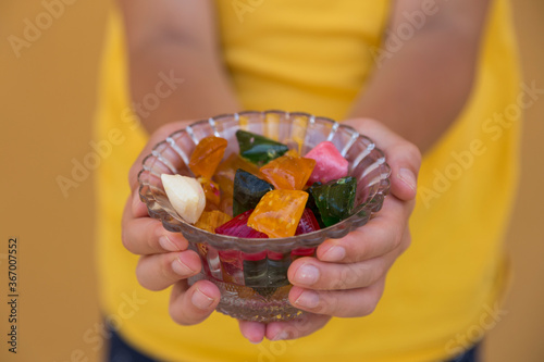 the child hold the colorful candies in the bowl service old humans for Muslim holidays, victim festival , mother or teacher day.
