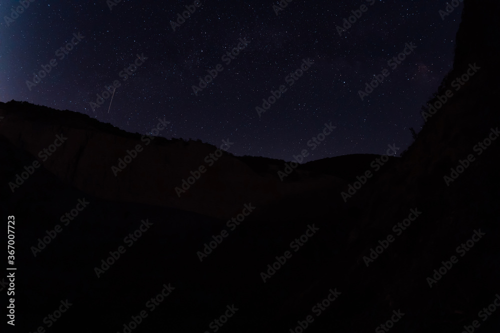 Night star sky with Milky way galaxy and canyon with mountains