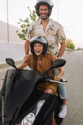 Portrait of couple driving a motorcycle, she is nice attractive lovely cheerful . He standing fooling having.