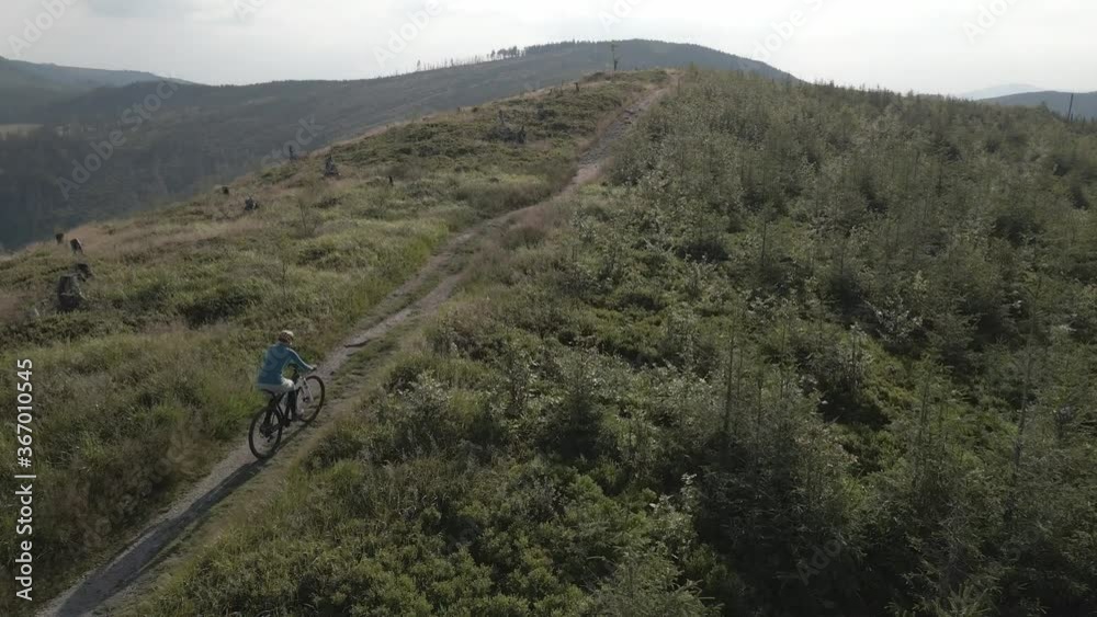 Aerial shot of mountainbike woman cycling in summer mountains landscape. Woman cycling MTB trail outdoor adventure.. Aerial shot of mountainbike woman cycling in summer mountains landscape. Woman cycling MTB trail outdoor adventure..