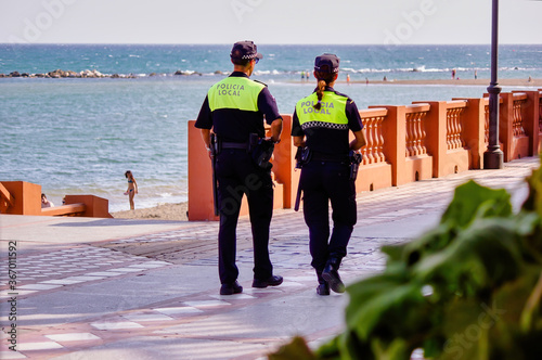 Malaga, Spain - September 04, 2015: Rear view of police security by the beach wearing cap in summer photo