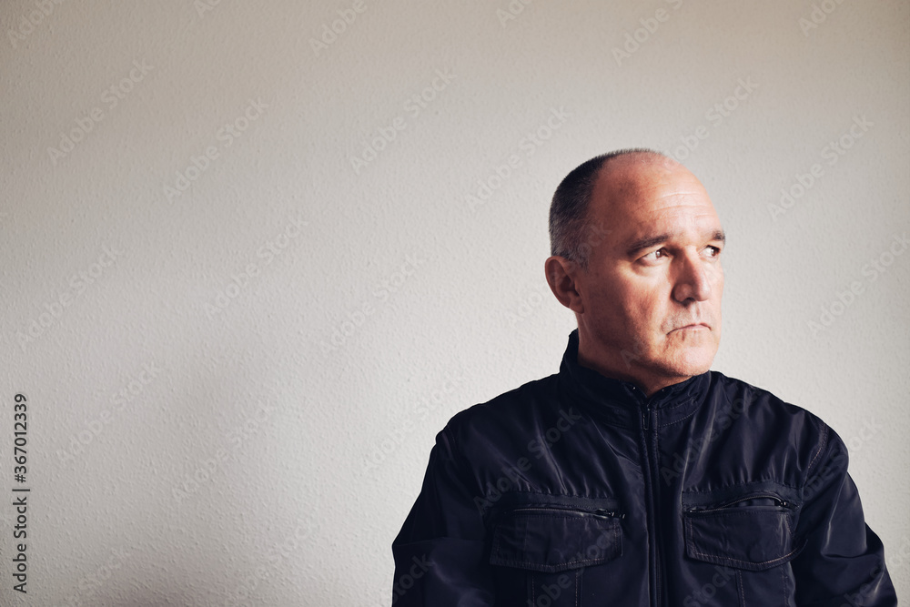 Serious middle-aged man on gray wall