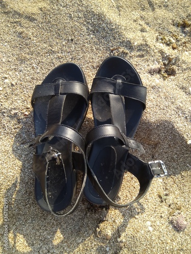 Black women's sandals on the sand on the Mediterranean coast close-up.