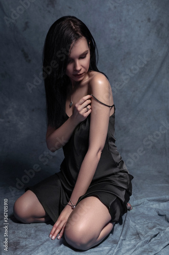 Brunette slim woman in sexy outfit on a neutral background. Studio portrait in seductive poses