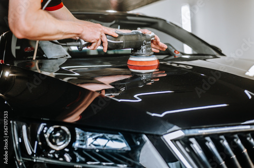 Professional detailing a car in car studio, hands with orbital polisher, scratching remover, vehicle care concept photo