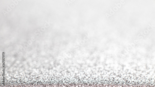 Silver festive Christmas background. Abstract shimmering background with bokeh silver lights. Shiny gradient with copy space. Silver wedding, new year concept. Selective focus. Glitter © Marykor